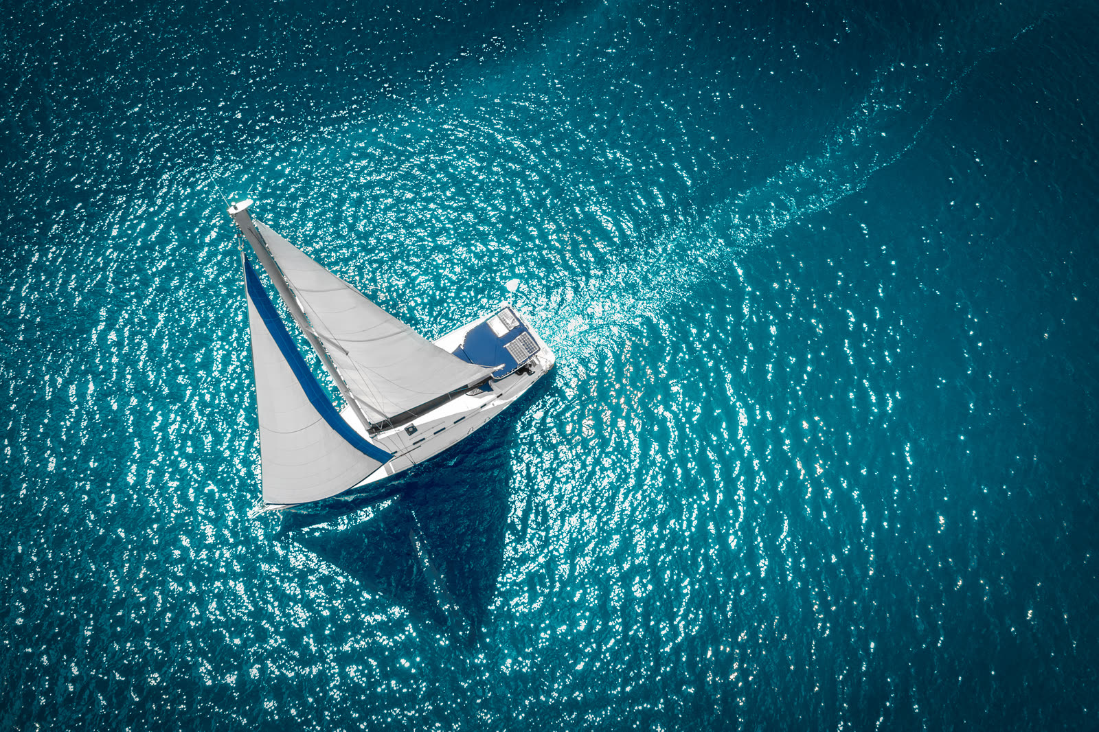 Velero navegando visto desde el aire sobre agua turquesa