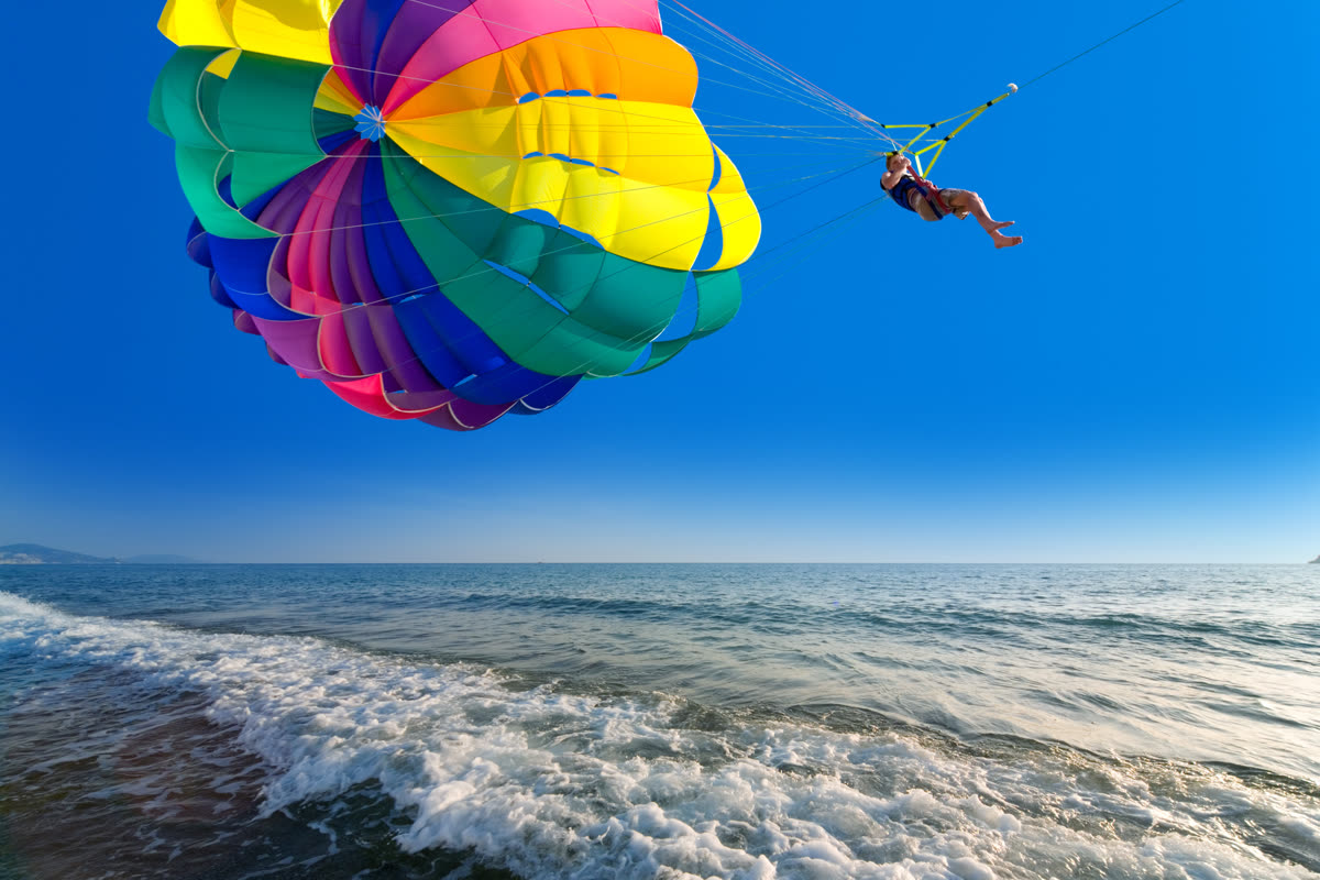 Paracaídas de parasailing en vuelo sobre la orilla